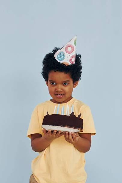 Happy little african american kid have fun indoors at birthday party holds cake. - Fotografie, Obrázek