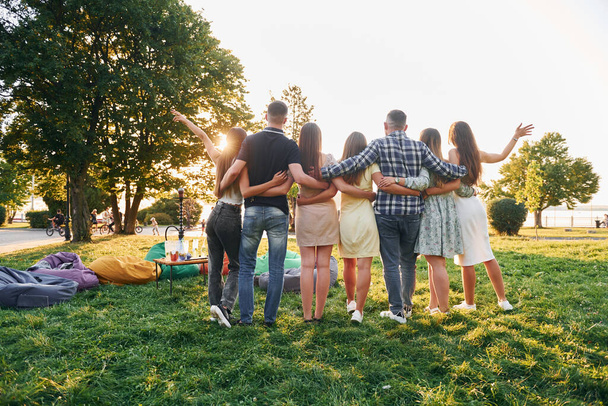 View from behind. Group of young people have a party in the park at summer daytime. - 写真・画像
