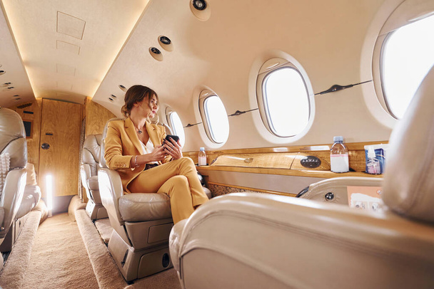 Woman in yellow clothes sits inside of private airplane. - Foto, Imagem