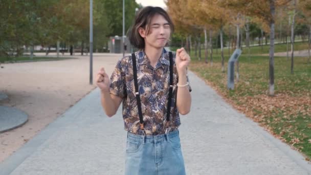 Jonge Taiwanese man glimlachend en dansend rock and roll in een park. - Video