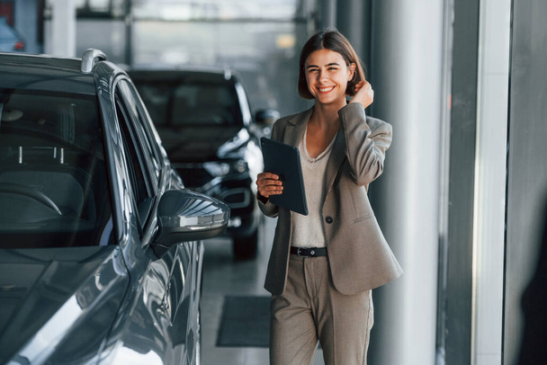 Woman is indoors near brand new automobile indoors. - Foto, afbeelding