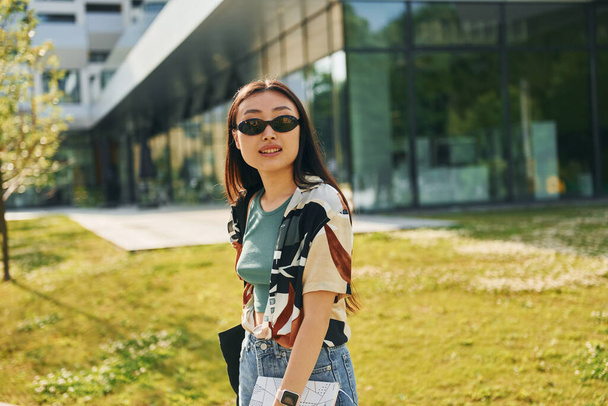 In sunglasses. Young asian woman is outdoors at daytime. - Fotografie, Obrázek