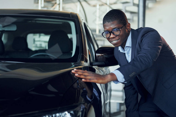 Jeune homme d'affaires afro-américain en costume noir est le salon de l'automobile. - Photo, image