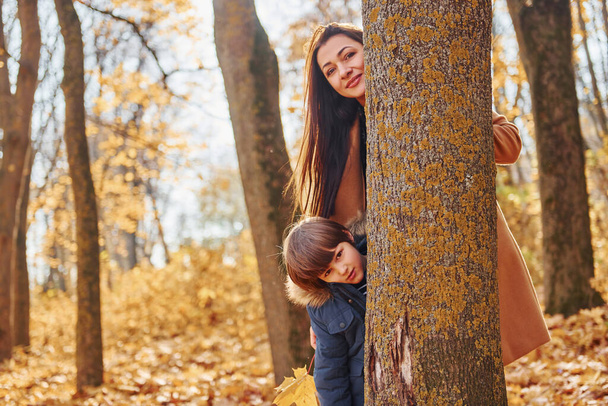 Mujer y niño alegres. Madre con su hijo se divierte al aire libre en el bosque de otoño. - Foto, imagen
