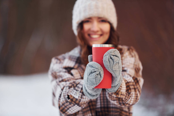 Beautiful woman in warm clothes have a walk in the winter forest. With drink. - Foto, Imagem