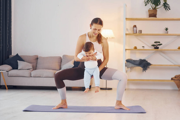 Teaching fitness. Mother with her little daughter is at home together. - Φωτογραφία, εικόνα