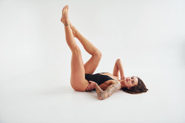 Lying down on the ground. Beautiful seductive sporty woman with sexy body is posing in the studio. - Zdjęcie, obraz