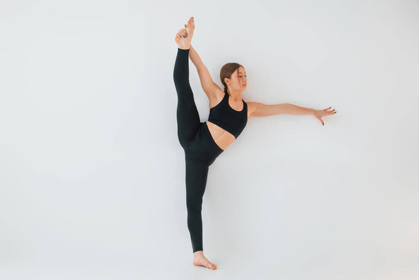 Cvičení na nohy. Mladá žena ve sportovním oblečení dělá gymnastiku uvnitř. - Fotografie, Obrázek