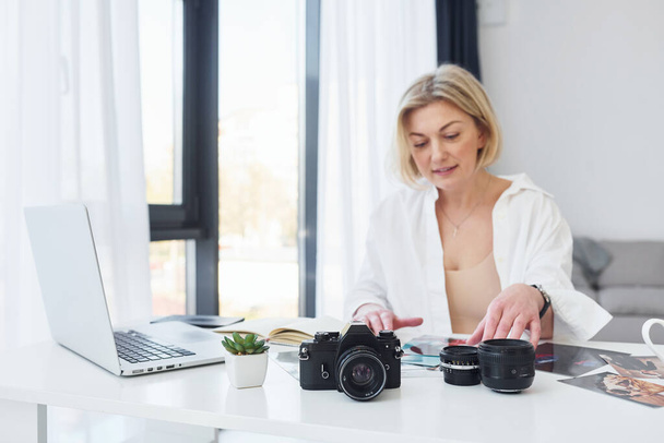 Middle-aged woman in elegant clothes is at home. Photographer with camera. - Photo, Image