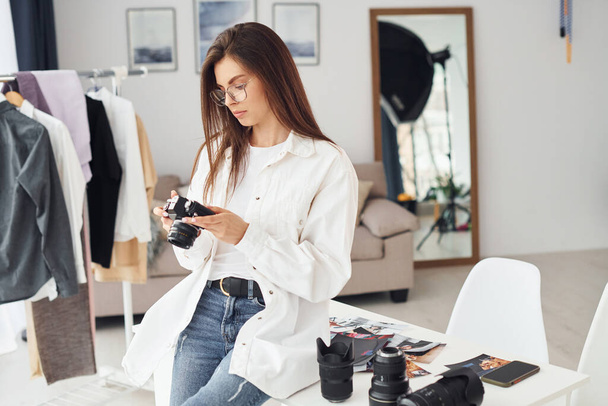 Female photographer in casual clothes is working indoors at daytime. - Фото, зображення