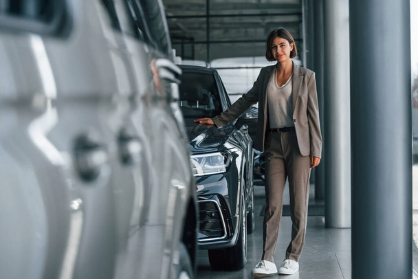Woman is indoors near brand new automobile indoors. - Fotografie, Obrázek