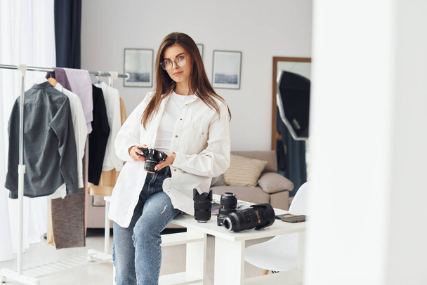 Female photographer in casual clothes is working indoors at daytime. - Foto, imagen