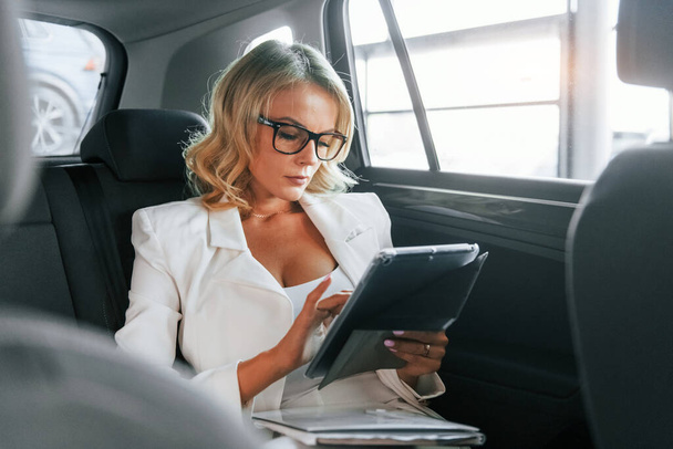 Working in the car. Woman in formal clothes is indoors in the autosalon. - Photo, image