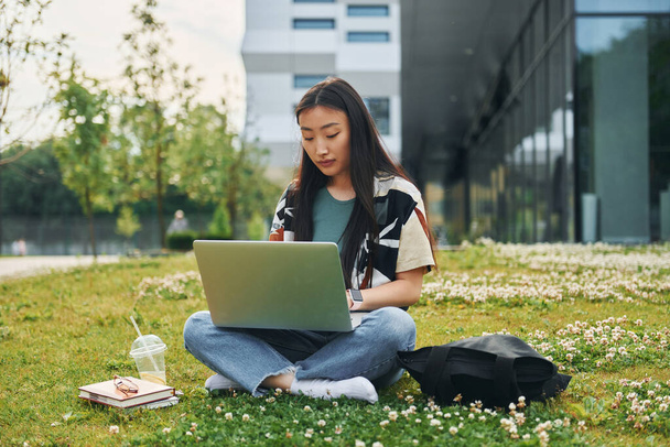 Uses laptop. Young asian woman is outdoors at daytime. - Fotoğraf, Görsel