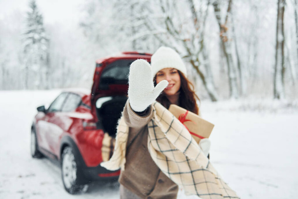 High five, gesture. Beautiful young woman is outdoors near her red automobile at winter time. - Foto, Imagem