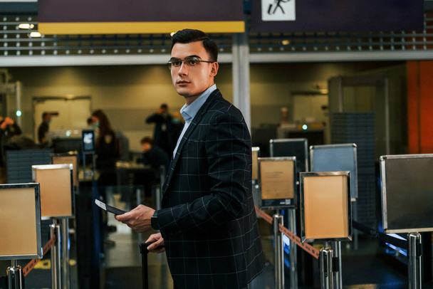 Modern background. Young businessman in formal clothes is in the airport at daytime. - Foto, imagen