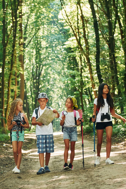 With map. Kids strolling in the forest with travel equipment. - Foto, Bild