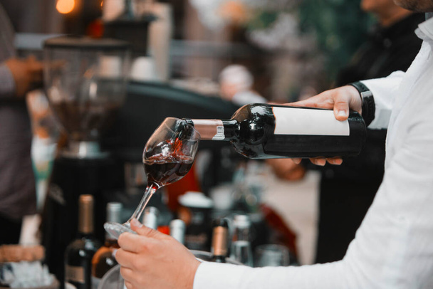 Бокал красного вина в руке на специальном мероприятии, специфическая дегустация алкогольных напитков. - Фото, изображение
