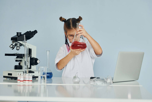 Little girl in coat playing a scientist in lab by using equipment. - Fotoğraf, Görsel