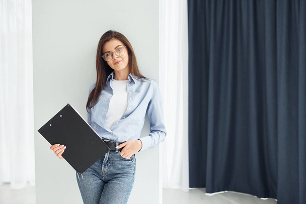 Young woman in glasses, formal clothes and with notepad standing indoors. - Foto, Imagem