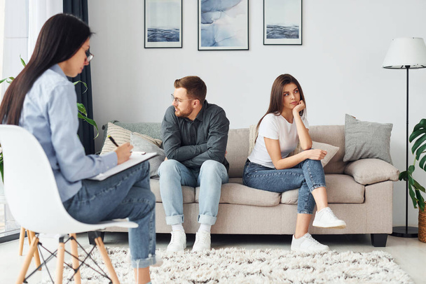 Couple is sitting on the sofa and working with female psychologist. - Photo, image