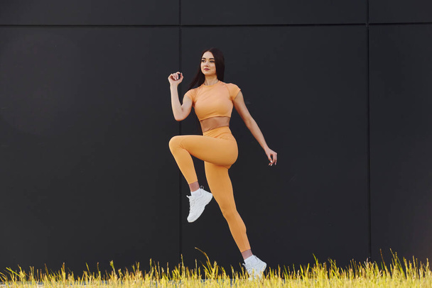 Training against black background. Young woman in sportswear have fitness session outdoors. - Foto, immagini