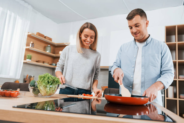 Frying food in a pan. Couple preparing food at home on the modern kitchen. - Φωτογραφία, εικόνα