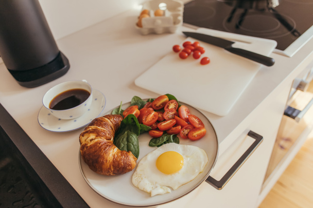 Delicious breakfast with egg and croissant near coffee in kitchen  - Photo, Image