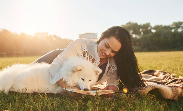 Woman with her dog is having fun on the field at sunny daytime. - Foto, imagen