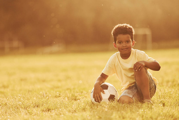 Illuminated by sunlight. African american kid have fun in the field at summer daytime. - Photo, Image