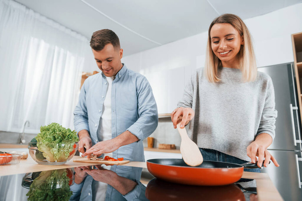 Frying food in a pan. Couple preparing food at home on the modern kitchen. - Φωτογραφία, εικόνα
