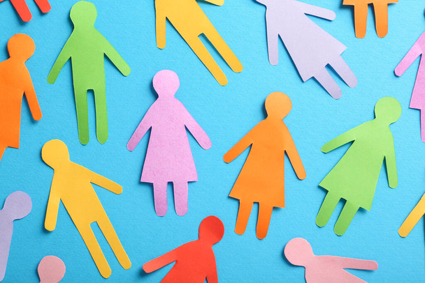 Many different paper human figures on light blue background, flat lay. Diversity and inclusion concept - Foto, imagen