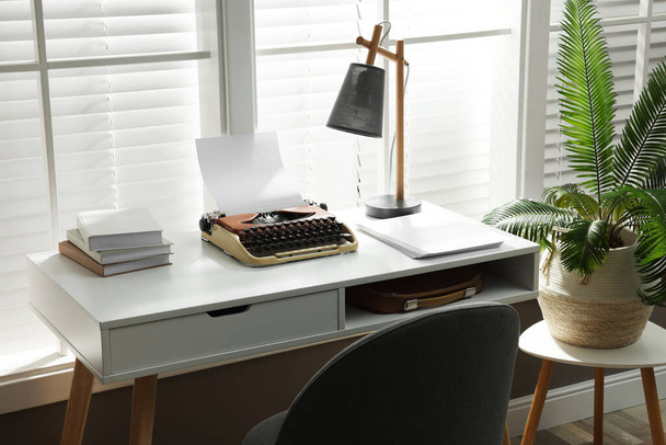 Άνετο χώρο εργασίας συγγραφέα με γραφομηχανή στο γραφείο μπροστά από το παράθυρο - Φωτογραφία, εικόνα