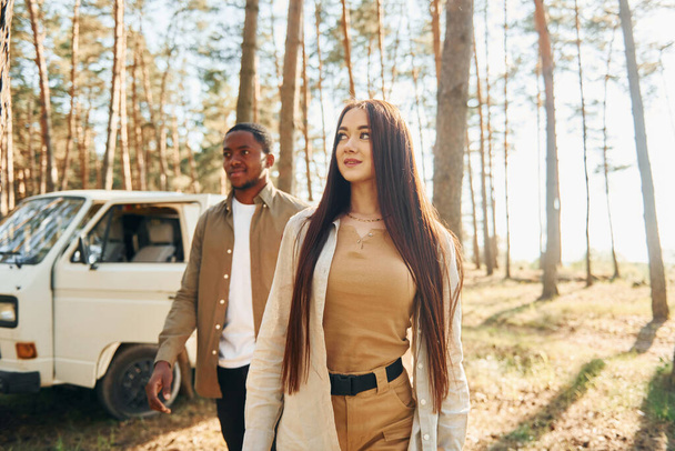Bus is behind. Young couple is traveling in the forest at daytime together. - Fotoğraf, Görsel