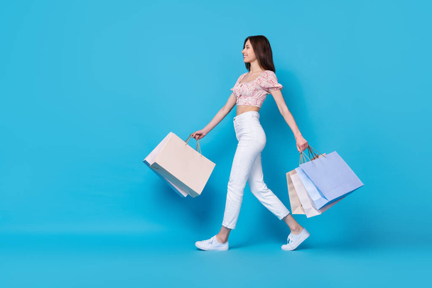 Full length profile side photo of nice lady shopaholic look empty space slim figure stylish outfit isolated on blue color background. - Foto, Bild