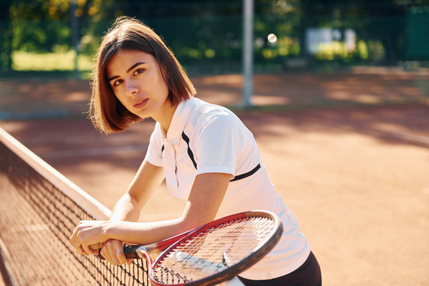 Standing with racket in hand. Female tennis player is on the court at daytime. - Fotoğraf, Görsel