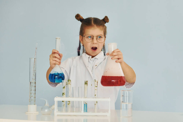 Scared little girl in coat playing a scientist in lab by using equipment. - Fotó, kép