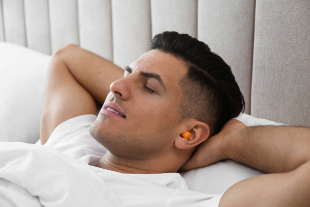 Man with foam ear plugs sleeping in bed - Φωτογραφία, εικόνα