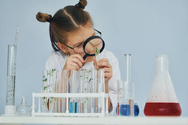 Works with test tubes. Little girl in coat playing a scientist in lab by using equipment. - Fotó, kép