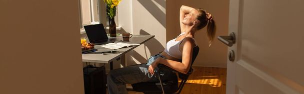 Side view of cheerful freelancer sitting near gadgets and breakfast at home, banner  - Foto, Bild