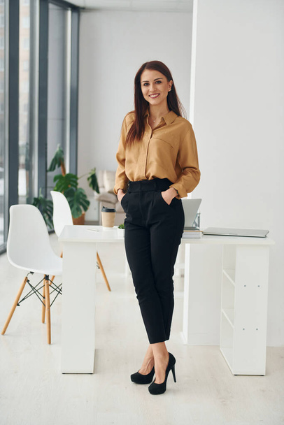 Woman in formal clothes is indoors in the modern office at daytime. - Foto, afbeelding