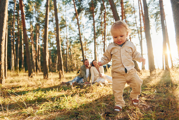 Little girl is running. Happy family of father, mother and little daughter is in the forest. - Fotografie, Obrázek