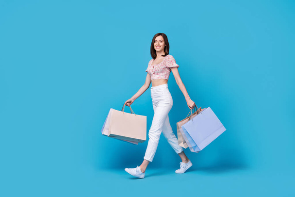 Full length photo of pretty cute lady dressed trendy clothes go store mall center empty space isolated on blue color background. - Foto, Bild