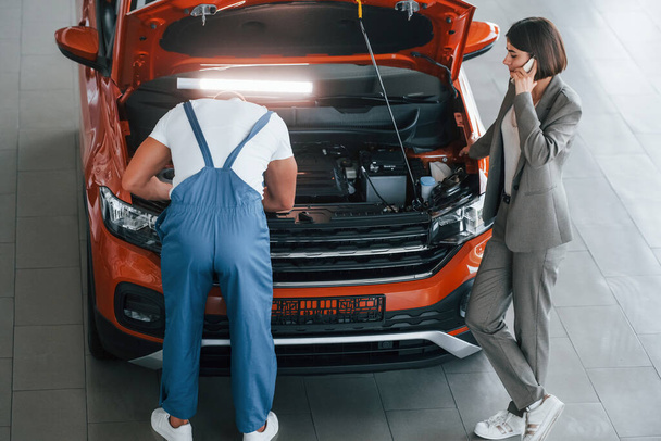 Propriétaire debout près de l'homme qui répare l'automobile à l'intérieur. Service professionnel. - Photo, image