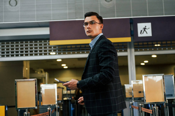 Modern background. Young businessman in formal clothes is in the airport at daytime. - Foto, Imagen