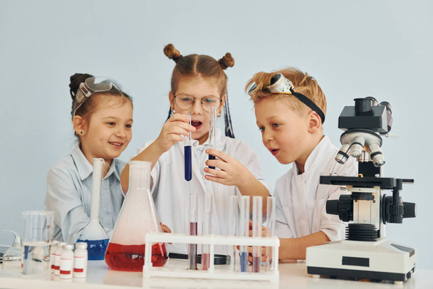 Test tubes with colorful liquid. Children in white coats plays a scientists in lab by using equipment. - Фото, изображение