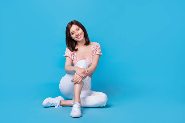 Photo of funny lady sitting floor empty blank space dressed fashiinable clothes hand touch leg isolated on blue color background. - Foto, Bild