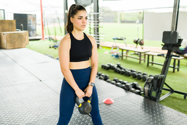 Mulher caucasiana atraente com um estilo de vida fitness pronto para levantar um peso kettlebell durante o exercício  - Foto, Imagem