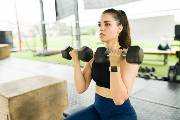Fitness urheilullinen nuori nainen käyttää käsipainoja ja treenata nosto painoja kuntosalilla - Valokuva, kuva