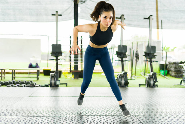 Mujer joven deportiva haciendo un ejercicio cardiovascular en el gimnasio y haciendo ejercicio haciendo límites laterales - Foto, imagen